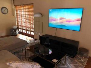 a living room with a flat screen tv on the wall at Executive suite with full kitchen & lounge in Pretoria