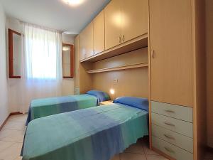 two beds in a room with cabinets and a bedroom at Le Briccole in Cavallino-Treporti