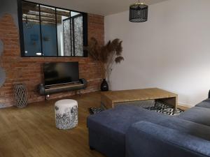 a living room with a blue couch and a brick wall at Au 19 de Lina in Hoerdt