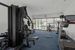 un gimnasio con varias máquinas de correr y una gran ventana en The Oasis Apartments, en Brisbane
