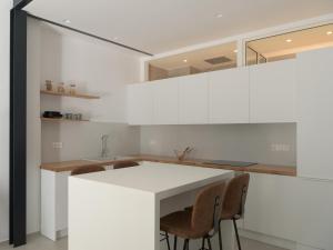 a kitchen with a white counter and chairs at Loft 26 in Ierapetra
