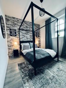 ein Schlafzimmer mit einem schwarzen Himmelbett und einer Ziegelwand in der Unterkunft Apartment 360 Grad mit direktem Blick aufs Schloss in Steinfurt
