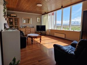 sala de estar con sofá, mesa y algunas ventanas en Helgafell Guesthouse, en Stykkishólmur