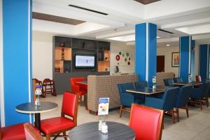 Holiday Inn Express McComb, an IHG Hotel في ماكومب: مطعم به طاولات وكراسي وتلفزيون