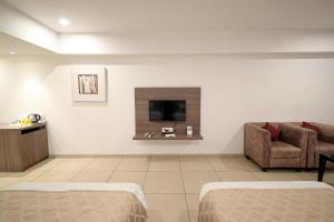 a living room with a couch and a tv on a wall at Hotel Dwarkamai, A Pure Vegetarian Hotel in Nagpur