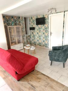 a living room with a red couch and a chair at Maison de 3 chambres avec jardin clos et wifi a Gefosse Fontenay a 1 km de la plage in Géfosse-Fontenay