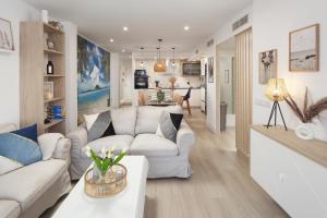 a living room with white couches and a kitchen at Apartamento Mediterráneo in Rincón de la Victoria