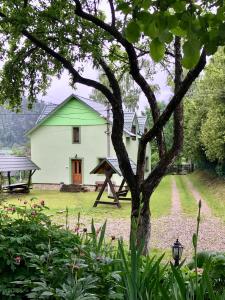 una casa blanca con un árbol en el patio en Goryanka Hotel, en Mykulychyn
