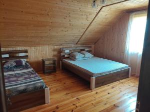 a bedroom with two beds in a wooden cabin at Сімейний куточок in Svityazʼ