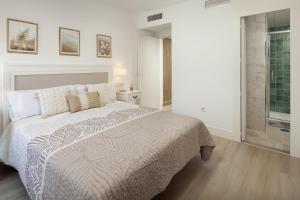 a white bedroom with a large bed and a window at Apartamento Mediterráneo in Rincón de la Victoria