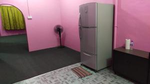 a pink room with a refrigerator and a fan at Sobey Laris Homestay WAKAF BHARU in Wakaf Baharu