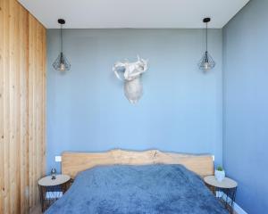 een slaapkamer met een blauwe muur en een bed met 2 tafels bij Alma house - Grey in Alma-Ata