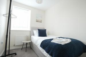 een slaapkamer met een bed met een blauwe deken en een raam bij Spacious 4 bedroom, perfect for contractors, families, private parking in Royal Wootton Bassett