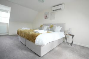 een witte slaapkamer met een groot bed met witte lakens bij Spacious 4 bedroom, perfect for contractors, families, private parking in Royal Wootton Bassett
