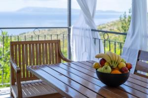a bowl of fruit on a wooden table on a balcony at Villa with Sea View in Podgora