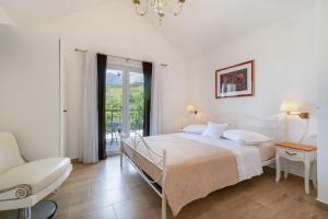 a white bedroom with a bed and a chair at Villa with Sea View in Podgora