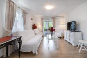 a living room with a white couch and a tv at Villa with Sea View in Podgora