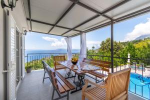 a patio with a table and chairs on a balcony at Villa with Sea View in Podgora