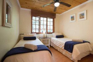 1 dormitorio con 2 camas y ventilador de techo en Areena Riverside Resort, en Kwelera