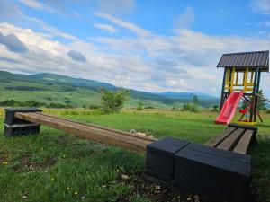 een houten bank met een schommel en een speeltuin bij Under Sky House - Vikendica - Manjača in Ključ