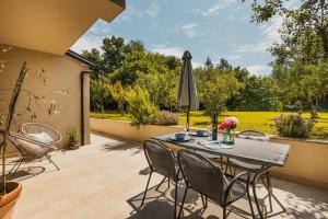 een terras met een tafel, stoelen en een parasol bij Apartments Olea in Novigrad Istria