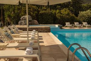 a pool with white lounge chairs and an umbrella at Paradise Art Hotel by Mr and Mrs White in Andros