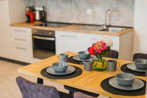 einem Holztisch mit vier Tassen und einer Vase Blumen in der Unterkunft Apartments Olea in Novigrad Istria
