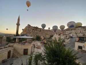 a group of hot air balloons flying over a city with a mosque at Cappadocia Fairy Tale Suites in Goreme