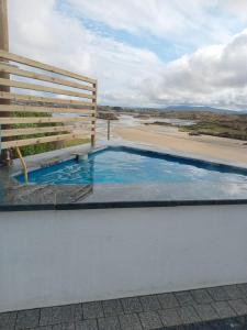 a swimming pool next to a bench and a beach at Cascade Lodge & Hot Tub in Donegal