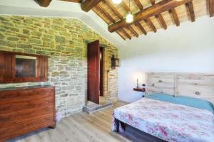 1 dormitorio con cama y pared de piedra en Casale Cantalena en Cortona