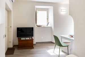 a living room with a television and a green chair at Borgo dei Nonni - Menaggio by LoveComo in Menaggio