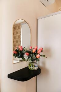 a vase of flowers on a shelf in front of a mirror at Casa Altarocca - Home Design in Tarquinia