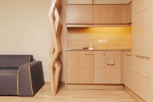 a small kitchen with wooden cabinets and a couch at Mana Suites & Sea SPA in Palanga +131 photos