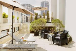 eine Dachterrasse mit Stühlen, Tischen und einem Sonnenschirm in der Unterkunft Argenta Tower Hotel & Suites in Buenos Aires