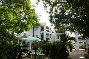 a large white building with a swimming pool and trees at Wayside Beach Apartments in Diani Beach