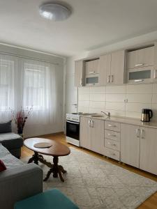Una sala de estar con una mesa y una cocina. en Prishtina Central Apartment, en Pristina