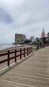 una passerella di legno accanto alla spiaggia con un edificio di Studio Calypso 5 a Sitio de Calahonda
