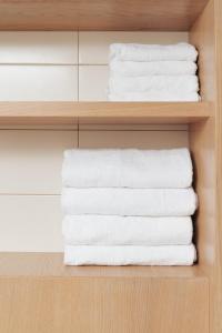 uma pilha de toalhas brancas numa prateleira em Mana Suites & Sea em Palanga