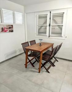 una mesa de madera y sillas en una habitación con ventanas en Appartement d'une chambre avec terrasse amenagee a Le Vauclin a 3 km de la plage, en Le Vauclin