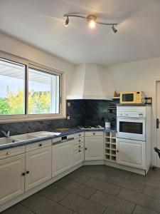 a kitchen with white cabinets and a sink and a microwave at Appartement des Grands Champs avec terrasse in Saint-Aignan +18 photos