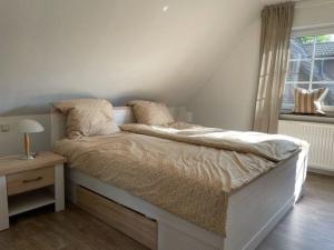 a bedroom with a bed with a nightstand and a window at Ferienhaus Jolufelu , Urlaub zwischen See und Golfplatz in Göhren-Lebbin