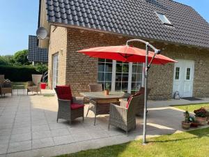 a table and chairs with a red umbrella on a patio at Ferienhaus Jolufelu , Urlaub zwischen See und Golfplatz in Göhren-Lebbin