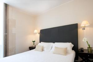 a bedroom with a white bed with a black headboard at Hotel Palazzo Cavalieri in Syracuse