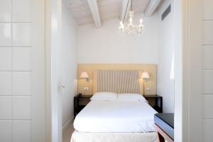 a bedroom with a white bed and a chandelier at Hotel Palazzo Cavalieri in Syracuse