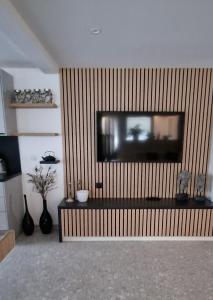 a living room with a television on a wooden wall at Moderne F3 - 10 min aeroport CDG - Paris - Parc Astérix - Disneyland Paris - Tour Eiffel - Champs Elysée - 15 min Parc des expositions Villepinte - 10 min Le Bourget - 5 min du Golf international de Roissy- JO 2024 in Le Thillay