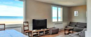 sala de estar con TV de pantalla plana y sofá en Maison de 6 chambres avec vue sur la mer jardin clos et wifi a Arromanches les Bains, en Corneville-sur-Risle