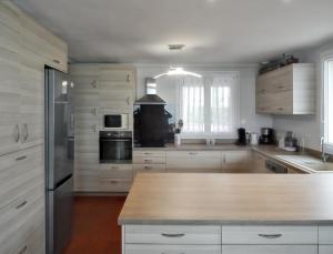 cocina con armarios blancos y encimera de madera en Maison de 6 chambres avec vue sur la mer jardin clos et wifi a Arromanches les Bains, en Corneville-sur-Risle
