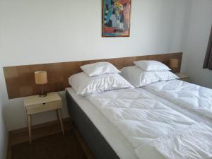 a bed with two pillows on it next to a table at Római-Víztorony Apartman in Dunaújváros