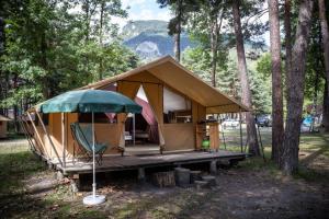 a tent in the woods with a green umbrella at Huttopia Bourg St Maurice in Bourg-Saint-Maurice
