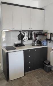a kitchen with white cabinets and a sink at Faros Sea View - Sifnos in Faros